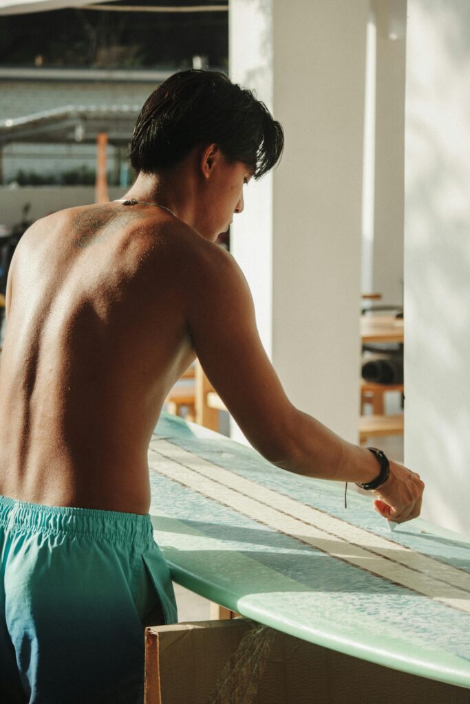 a guy waxing his surfboard