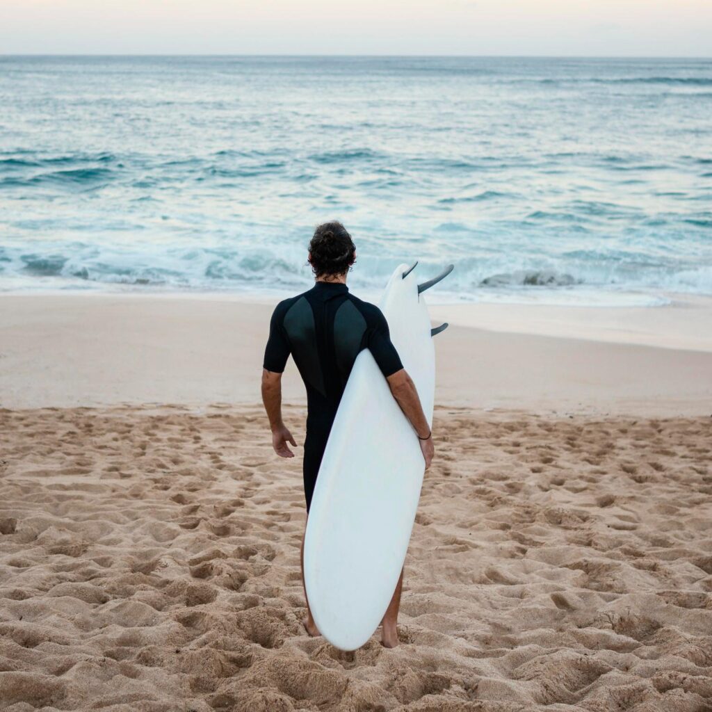 a man with his surfboard at the beach