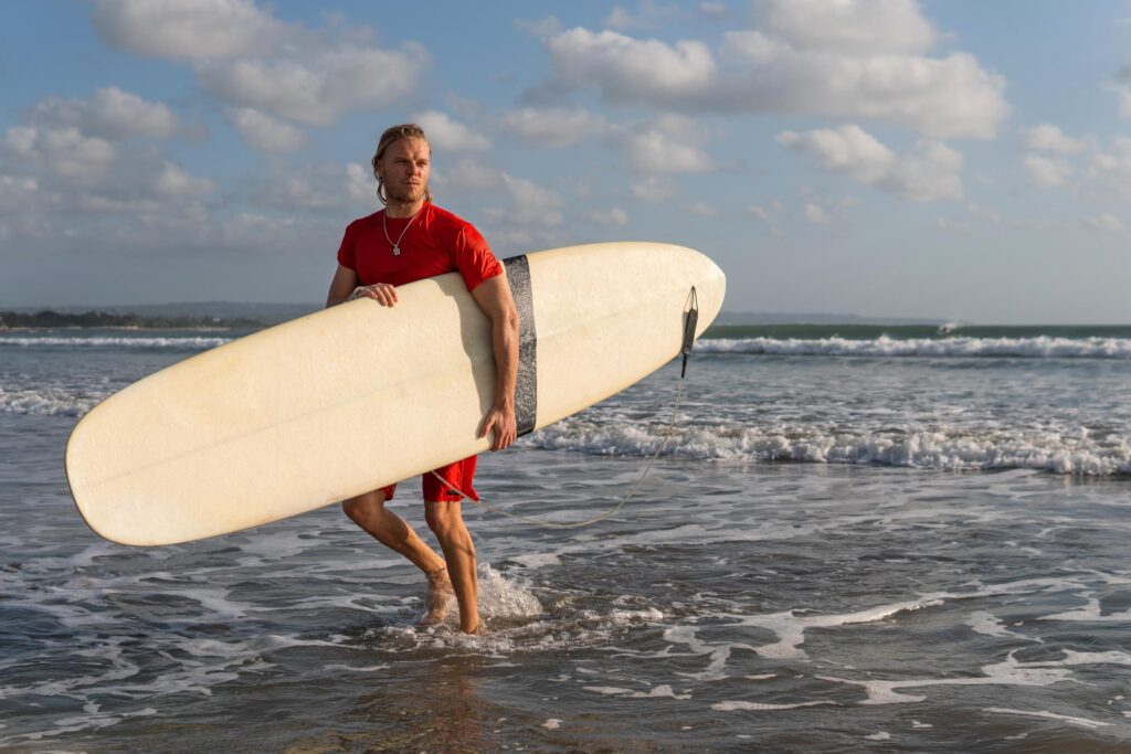 a fit person holding his surfboard