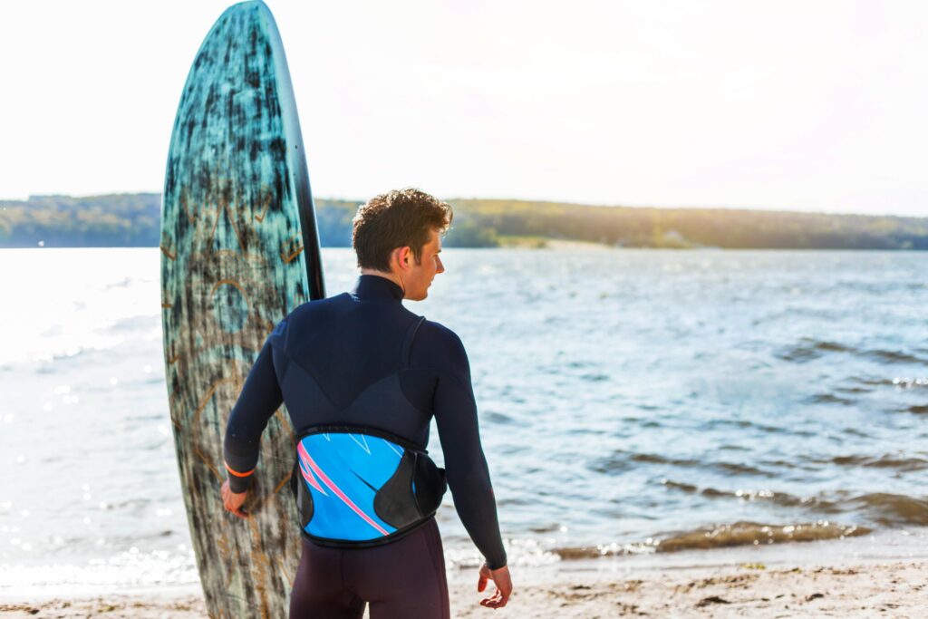 a surfer wearing his wetsuite and holding his srufboard