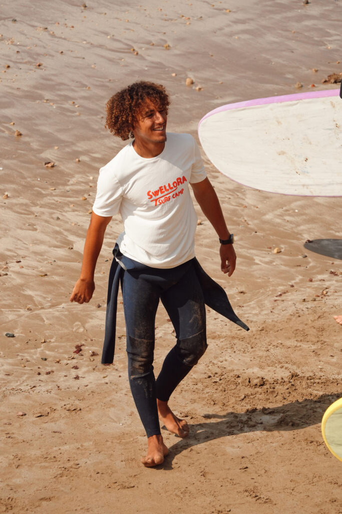 EasyRide Surf School Instructor in Imsouane Local surf instructor in a Swellora shirt walking on Imsouane beach after a surf lesson